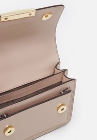 Portafoglio in pelle rosa pallido con finiture dorate, dotato di chiusura a scatto, più scomparti per carte e un compartimento interno con zip.