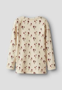 Chemise à manches longues en tissu côtelé, jaune pâle avec un motif floral rouge et vert. Elle a un col rond et des ourlets cousus.