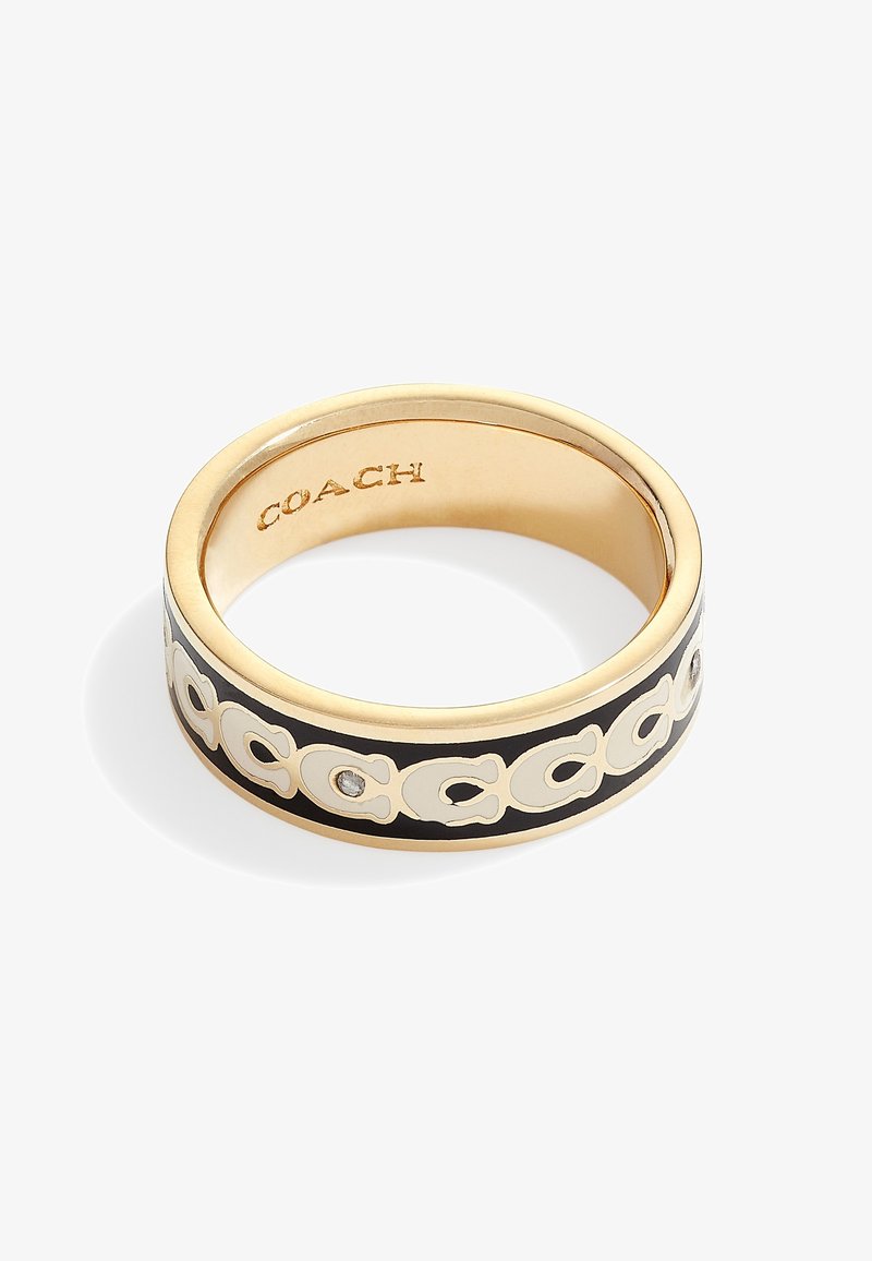 Bague en métal doré avec émail noir et motif logo Coach blanc, petit cristal incrusté et gravure "COACH" à l’intérieur.