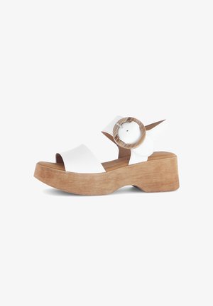 Weiße Plateausandalen mit einem Holzfußbett, ausgestattet mit einem breiten Vorderriemen und einem kreisförmigen Schnallendetail am Knöchelriemen.