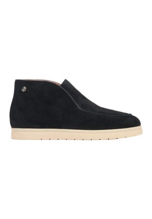 Schwarze Wildleder-Ankle Boots mit runder Zehenform, flachem Profil und cremefarbener Gummisohle; sie haben minimale Nähte und ein kleines Logo als Akzent.