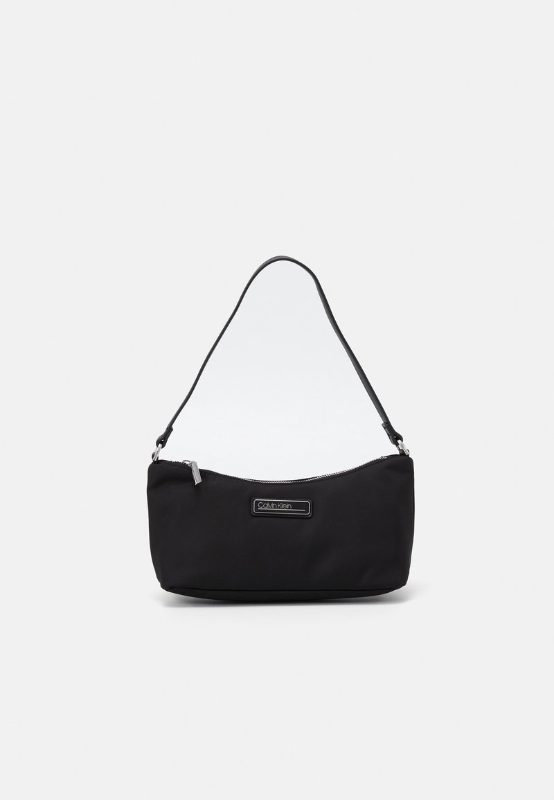 Sac à épaule noir Calvin Klein avec fermeture éclair et bandoulière simple, forme rectangulaire, design minimaliste sur fond blanc.