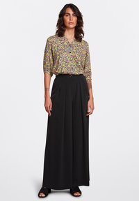 Blusa a fantasia floreale con maniche corte, scollo a V e pantaloni neri a vita alta con gamba ampia. Tessuto morbido con una silhouette fluida.