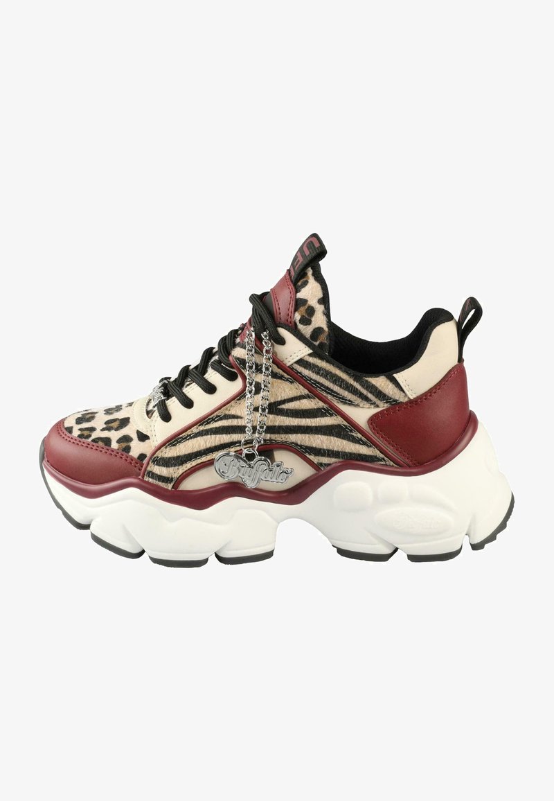 Chunky sneakers med et beige og brunt dyremønster, røde skinnakkenter, svarte snørebånd og en sølvcharms festet på siden.