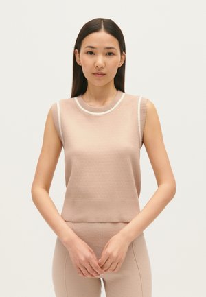 Top senza maniche beige chiaro con scollatura e armholes a costine, caratterizzato da un tessuto testurizzato e design aderente, abbinato a pantaloni aderenti coordinati.
