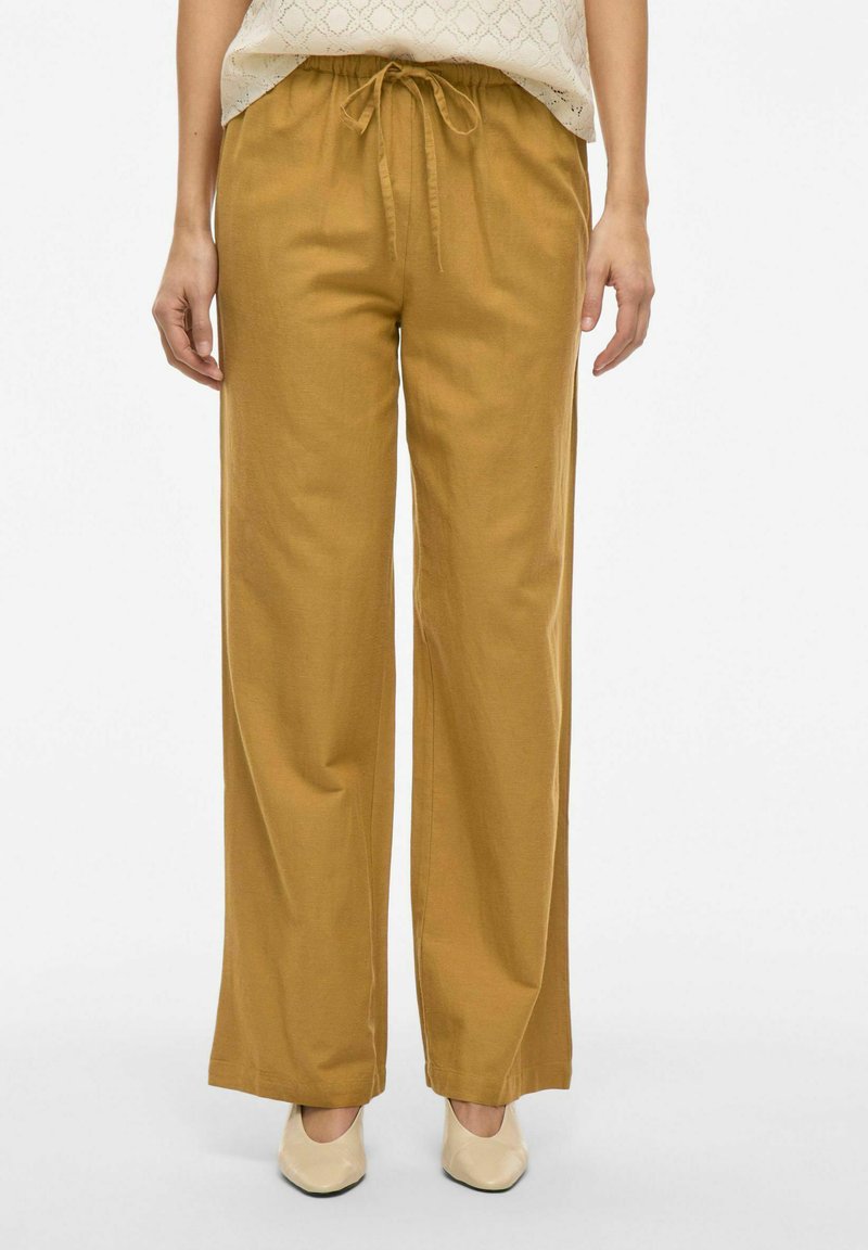 Pantalones de pierna ancha en tejido amarillo mostaza, con una cintura elástica y cordón ajustable, además de una textura suave.
