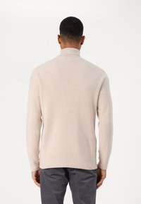 Helles beiges, geripptes Sweatshirt mit hohem Kragen, langen Ärmeln und geradem Schnitt; bietet einen strukturierten Stoff für Wärme und Komfort.
