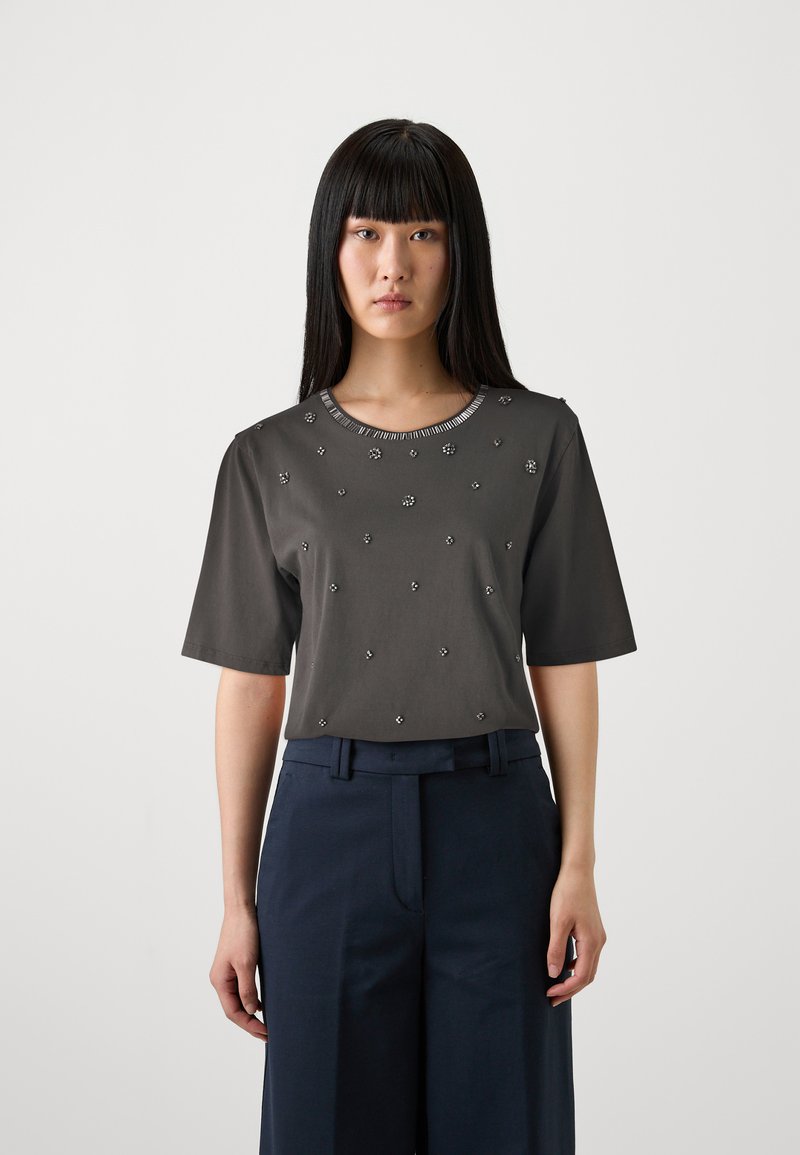 Tumši pelēks īsās piedurknes tops ar noapaļotu dekoltē, rotāts ar mazām dekoratīvām detaļām, apvienots ar tumši ziliem plats kāju biksēm.