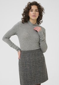 Grey ribbed turtleneck top paired with a knee-length, plaid skirt featuring shades of grey and brown, textured fabric, and side pockets.