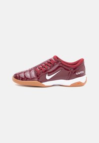 Sarkans lakots ādas sporta apavu modelis ar izšūtu dizainu, balto Nike logo un gumijas zoli; ar sarkaniem šķērsenisko sašuvumiem un mīkstinātu apkaklīti.