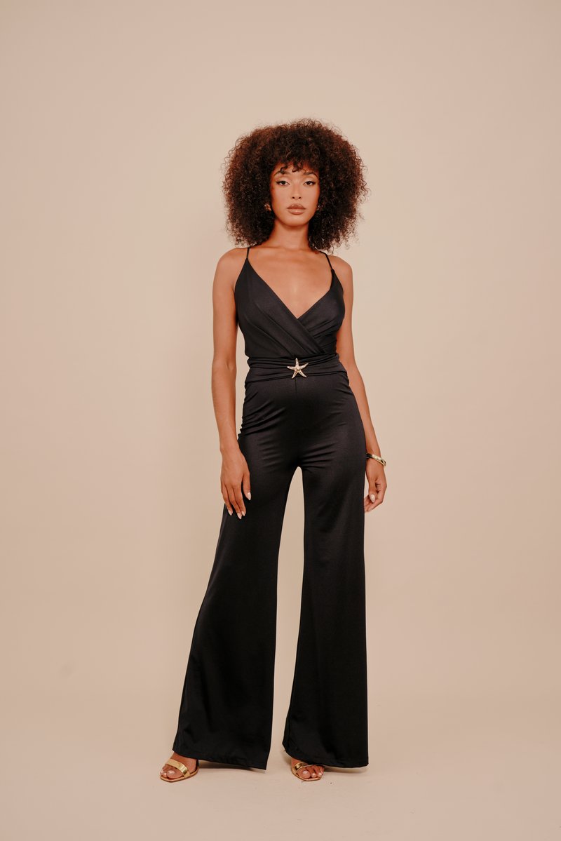 Μαύρη ολόσωμη φόρμα με βαθύ V λαιμόκοψη �και λεπτές τιράντες, στενότερη στη μέση με μεταλλική αγκράφα σε σχήμα αστεριού, με φαρδιές παντελόνες.