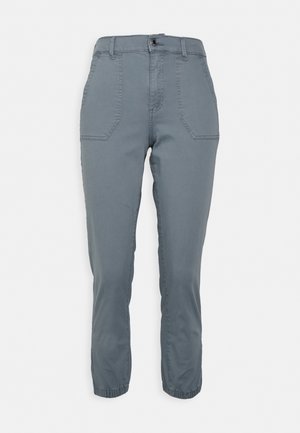 Pantalones grises hechos de una tela suave, con un ajuste slim, puños elásticos y dos bolsillos frontales con un cierre de botón a presión visible.