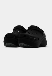 Toufões pretos de borracha com orifícios de ventilação, tira traseira, solas texturizadas e design com biqueira arredondada. Leves e fáceis de limpar.