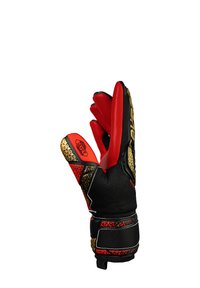Guantes de portero en negro y rojo con un agarre texturizado. Presenta detalles en dorado y un patrón distintivo en la parte posterior de la mano y la correa de la muñeca.