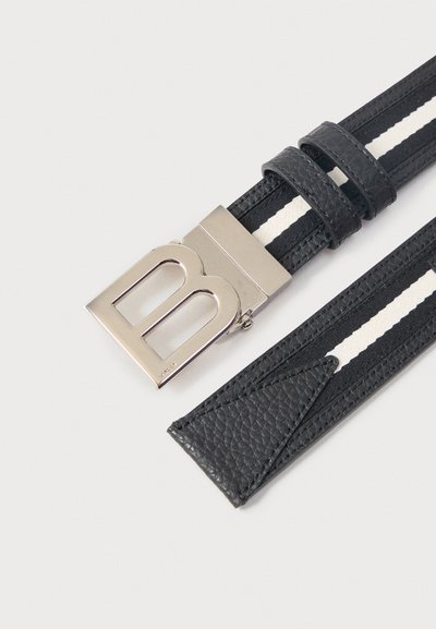 Μαύρη δερμάτινη ζώνη με λευκή ρίγα και ασημένια αγκράφα σε σχήμα γράμματος "B" σε ανοιχτό φόντο.