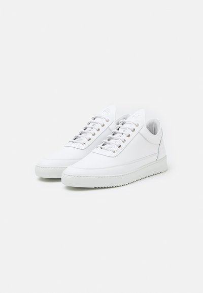 Zapatillas de cuero blanco con una textura suave, que presentan un diseño de bajo perfil, punta redonda y ojales plateados para los cordones.