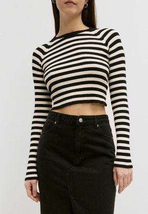 Pull cropped à rayures noires et blanches avec une texture côtelée et des manches longues, associé à une jupe en denim noire taille haute.