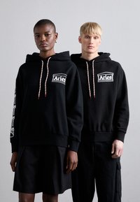 Zwarte hoodies met geborduurd "Aries" logo op de borst en mouw. Beschikt over contrasterende trekkoorden en een relaxte pasvorm.