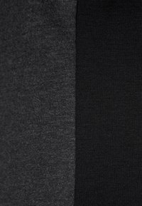 Échantillon de tissu en coton, moitié gris foncé et moitié noir uni, avec une texture lisse et une légère extensibilité, présentant une répartition uniforme de la couleur.