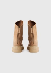 Bottines en cuir tan avec une texture lisse, fermetures éclair à l'arrière et une épaisse semelle en caoutchouc beige. Design simple et moderne.