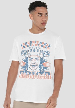 Young man wearing a white t-shirt with a graphic of a person in a helmet and text "You can't spell America without Erica" in red and blue.