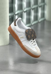 Fehér sneaker barna mintás nyelvvel, bézs részletekkel és gumi talppal. Tartalmaz fűzőt, logo márkázást és sima textúrát.