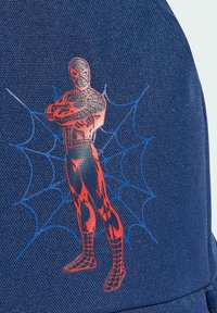 Tmavomodrý batoh s červenou grafikou Spider-Mana na pozadí dizajnu pavučiny, vyrobený z odolnej tkaniny s textúrovanými detailmi povrchu.