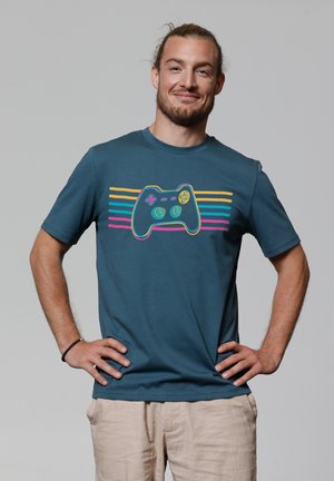 Blue cotton t-shirt featuring a graphic of a game controller with colorful horizontal stripes in pink, yellow, and teal across the front.