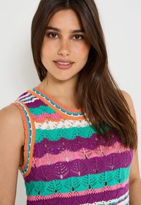 Top de ganchillo sin mangas colorido con rayas moradas, rosas, verdes y naranjas. El diseño incluye patrones de encaje y un escote acanalado.