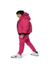 Chaqueta acolchada rosa con detalles en negro y capucha, combinada con pantalones rosas. Zapatillas altas blancas presentan un logo negro en el lateral.