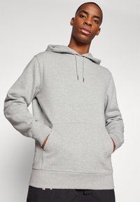 Gray hooded sweatshirt with a kangaroo pocket, drawstring closure, and ribbed cuffs, made from soft, textured fabric.