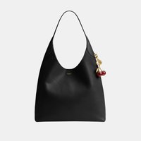 Sac à bandoulière en cuir noir avec une seule sangle, petit logo doré et un porte-clés cerise doré attaché sur le côté.