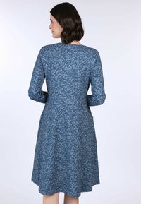 Blaues Blumenkleid mit langen Ärmeln, tailliertem Oberteil und ausgestellt Rock. Hergestellt aus weichem Stoff mit einem strukturierten Muster und seitlichen Taschen.