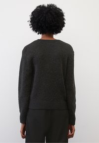 Pull en maille gris foncé avec manches longues, encolure ronde et ourlet côtelé. La texture semble douce et duveteuse, avec une coupe ample et décontractée.