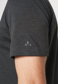 Dunkelgraues kurzärmliges Shirt aus strukturiertem Stoff. Es hat ein dezentes, graues Logo auf dem linken Ärmel und einen flach genähten Saum.