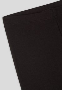 Czarne legginsy wykonane z miękkiej, elastycznej tkaniny. Posiadają gładką fakturę i przeszywany szew wzdłuż pasa, co zapewnia trwałość.