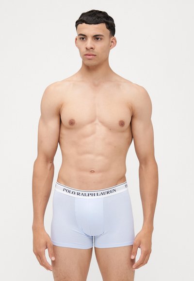 Svetlo modri bokserice z belim pasom, na katerem je črn napis "POLO RALPH LAUREN". Narejene so iz gladkega materiala, imajo oprijet kroj in segajo do sredine stegna.