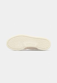 Suola di scarpa Reebok beige che mostra un motivo a diamante e un'area testurizzata circolare su sfondo bianco.