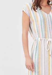 Robe rayée en tissu doux avec un col en V, des manches courtes, un devant à boutons et une taille à cordon. Les couleurs incluent le bleu, le jaune et le rose.