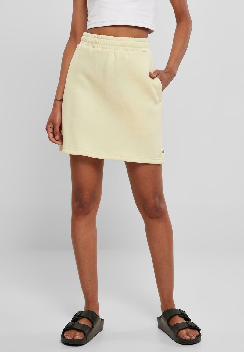 Falda amarilla claro, de largo hasta la rodilla, de corte relajado con una cinturilla elástica y bolsillos laterales. Fabricada en un tejido suave y texturizado.