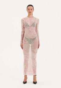 Dlouhé, přiléhavé šaty z průhledné, lehké tkaniny s růžovým květinovým vzorem. Vysoký límec, dlouhé rukávy, délka až k podlaze, zkombinované s černými podpatky.