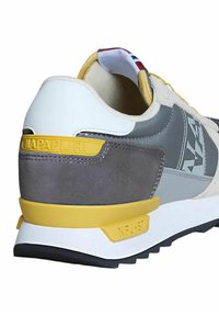 Sneakers con una toma grigia in pelle scamosciata e tessuto, tallone bianco e dettagli gialli. Presentano un logo sul lato e una suola nera testurizzata.