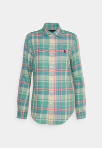 Grön rutmönstrad skjorta med knappar som har krage, långa ärmar och en liten röd logotyp. Mönstret inkluderar blå, gula och röda accenter.