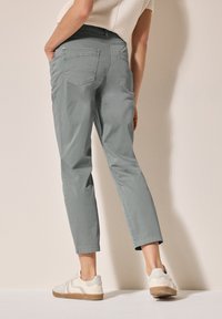 Pantaloni grigi a sigaretta realizzati in tessuto leggero, con tasche laterali e una vita aderente. Abbinati a sneaker off-white.
