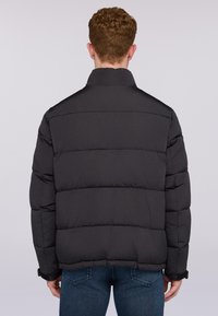 Svart puffjacka med hög krage och horisontellt quiltade paneler. Har elastiska ärmmuddar och en avslappnad passform. Lämplig för kallt väder.