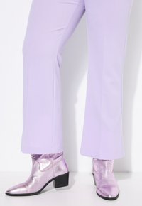 Metalen lila enkellaarsjes met een spitse neus en een lage blokhak, gecombineerd met lavendel kleurige broek. Gladde textuur met subtiele ontwerpdetails.