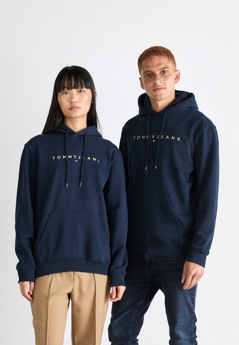 Mornarsko dukserice od mješavine pamuka s džepovima za kengure. Zlatni logo "TOMMY JEANS" na prsima, sa kapuljačama koje se mogu povući i rebrastim manžetama.