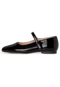 Zapato plano de charol negro estilo Mary Jane con punta redondeada y pequeño tacón, que presenta una correa prominente a través del empeine.