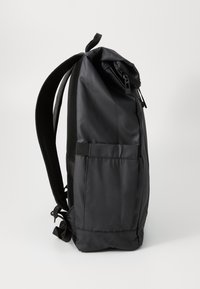 Sac à dos noir fabriqué en nylon durable. Il dispose d'un compartiment supérieur zippé, de bretelles en maille, d'une poche latérale et d'un design élégant et épuré.