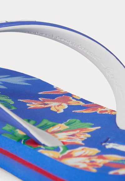 Niebieska japonka z białymi paskami, ozdobiona tropikalnymi kwiatowymi wzorami w kolorach pomarańczowym, żółtym i zielonym oraz wytłoczonym napisem na pasku.